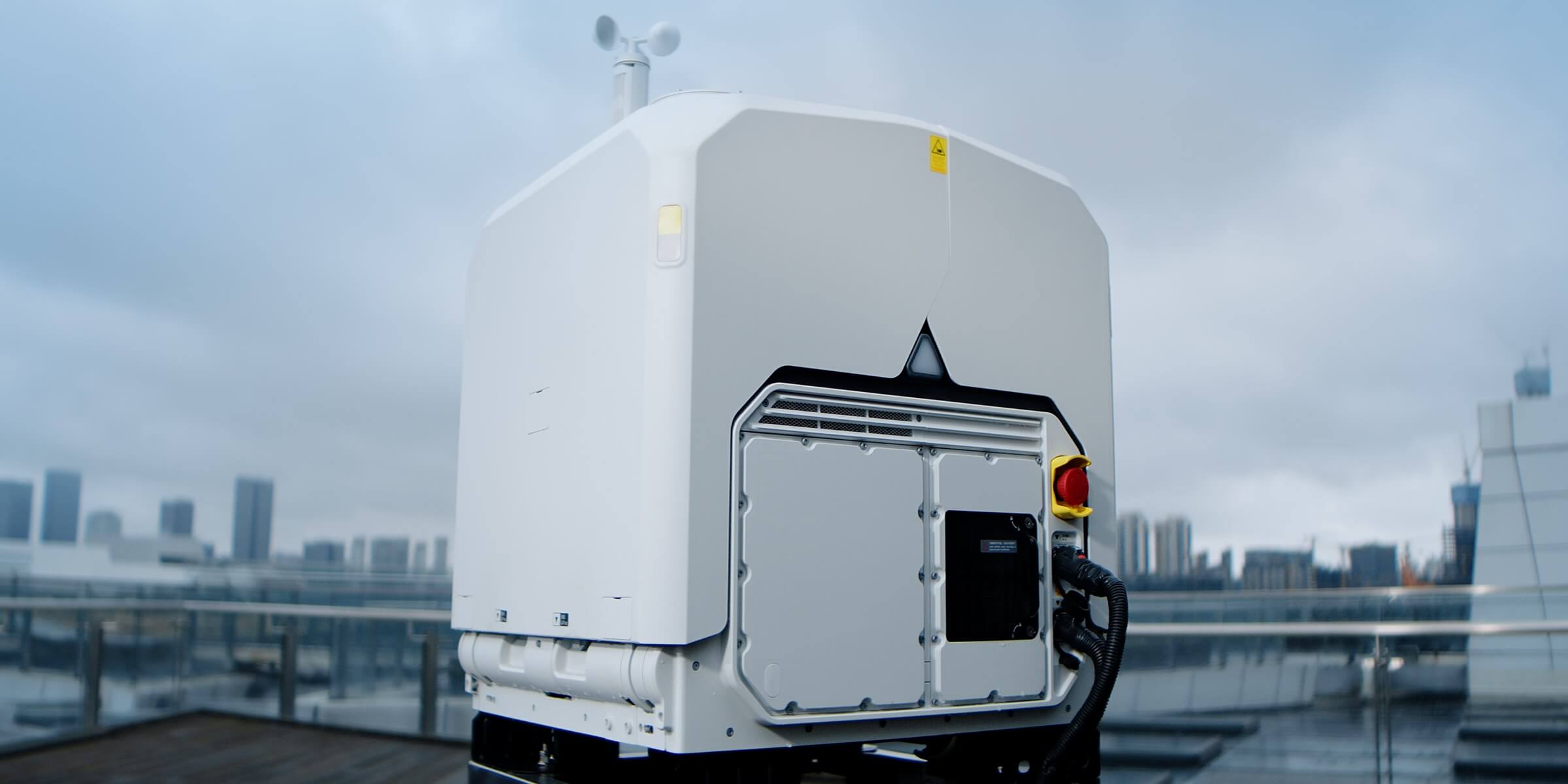 DJI Dock 4 mounted on a level rooftop surface with a city behind it.