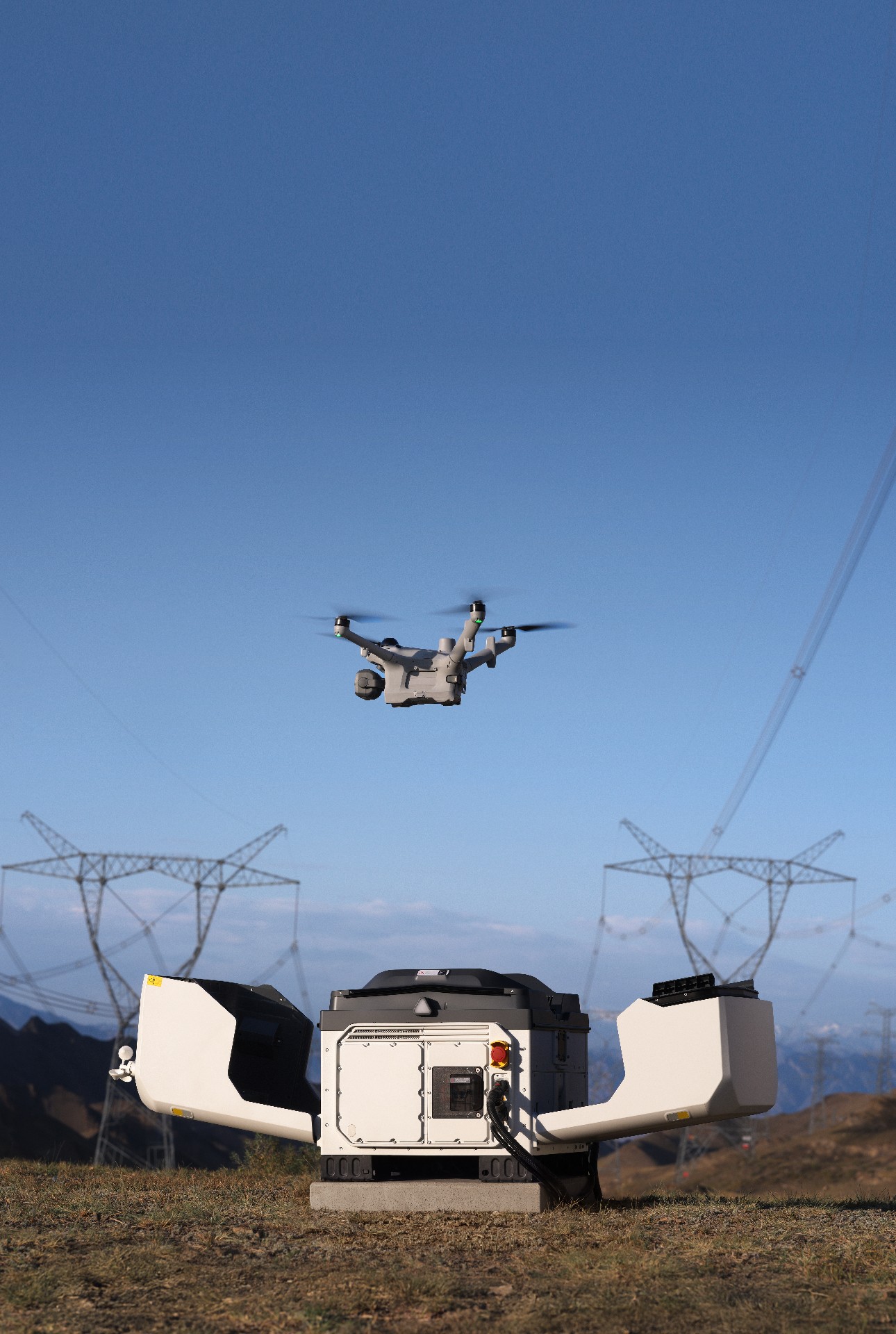 DJI Matrice 5TD launching from an open DJI Dock 4 at a remote hillside site beneath transmission towers, from official DJI imagery.