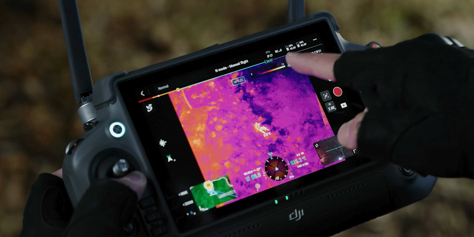 Field technician holding a DJI controller displaying a live radiometric thermal image during a drone inspection.