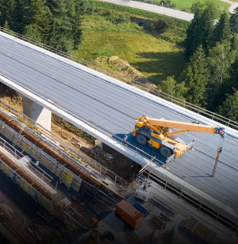 Aerial drone view of a crane working on a bridge deck under construction, from official DJI Dock 4 imagery.
