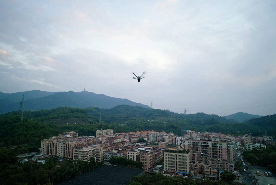 DJI enterprise drone in flight above a dense urban construction area.