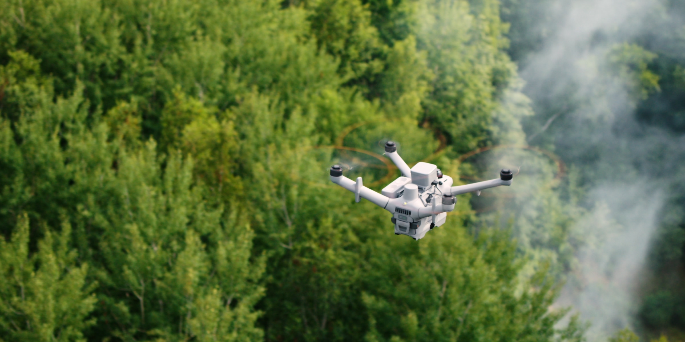 DJI Matrice 5TD flying over a forest toward rising smoke, from official DJI imagery.