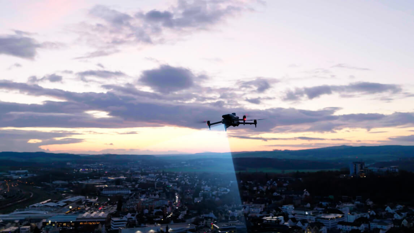 DJI Matrice drone flying with an inspection spotlight over a Canadian utility service area at dusk.